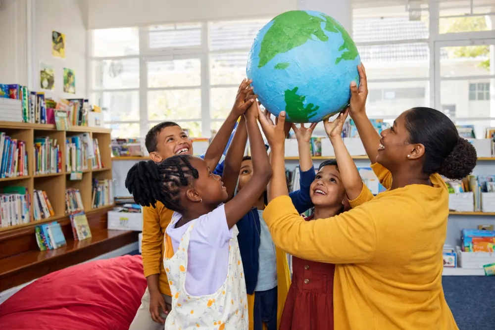 Children and a practitioner holding a globe together in a classroom