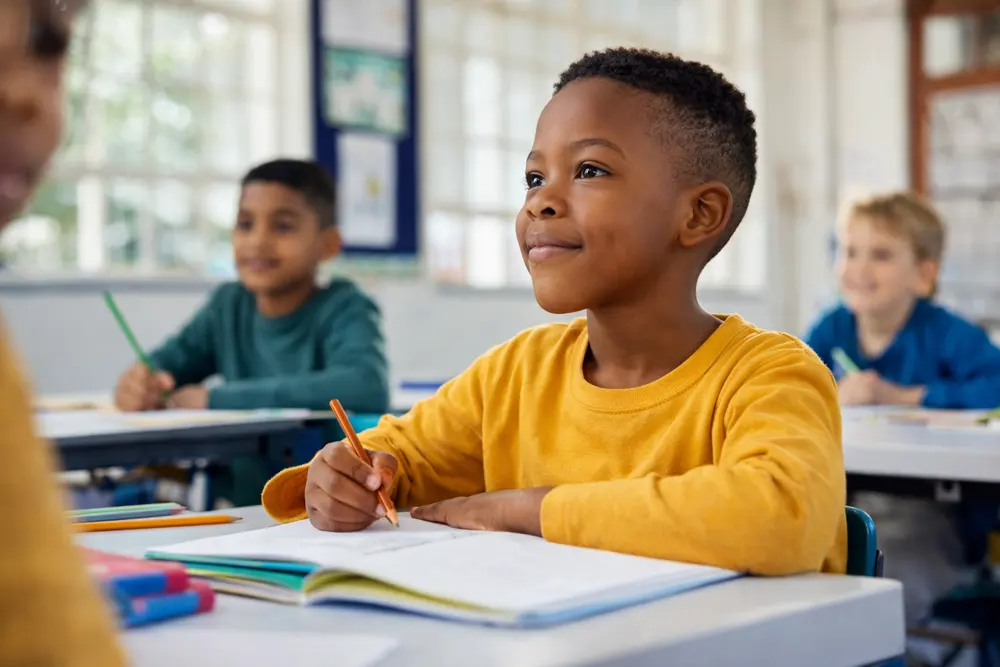 A young learner writing at a classroom desk