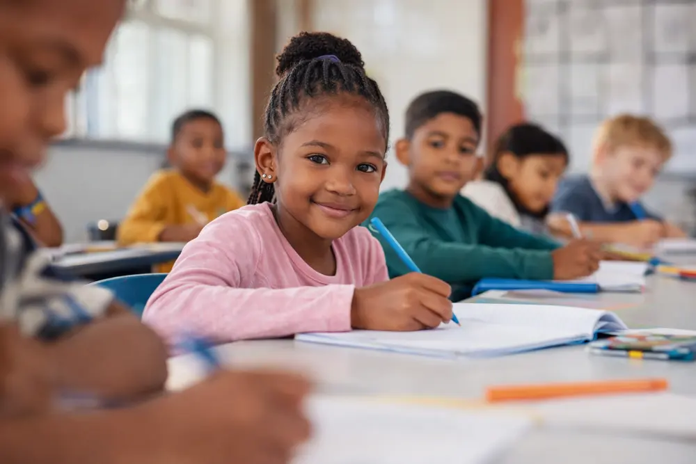A learner working at a desk in a bright classroom